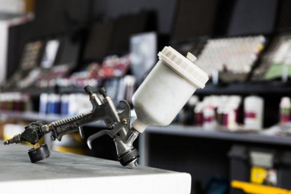 Closeup of paint-spray gun on table in professional car painting workshop